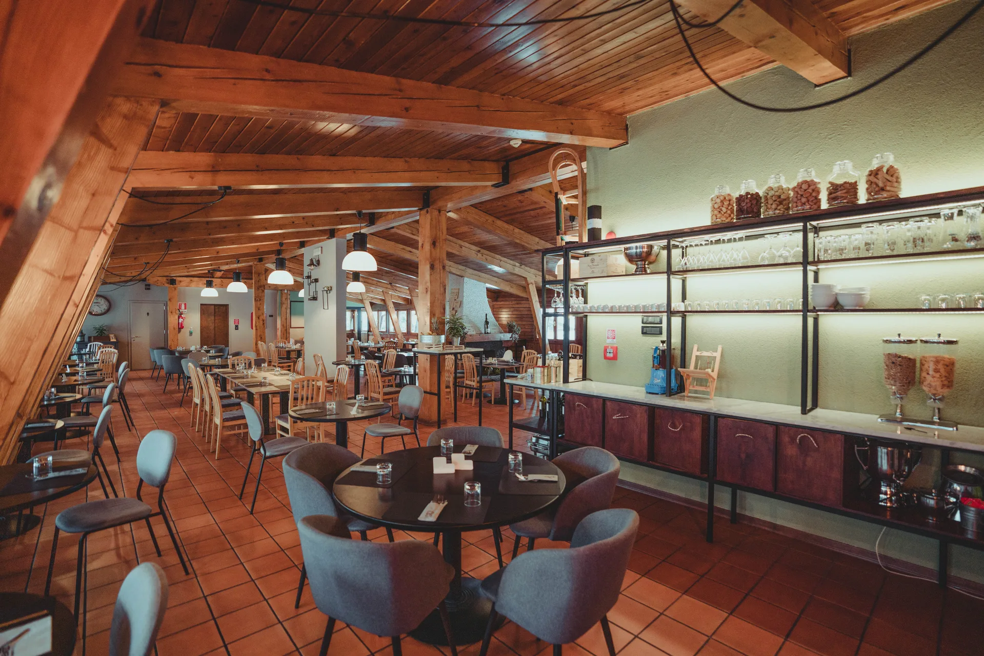 Sala ristorante con travi in legno, tavoli apparecchiati e bancone