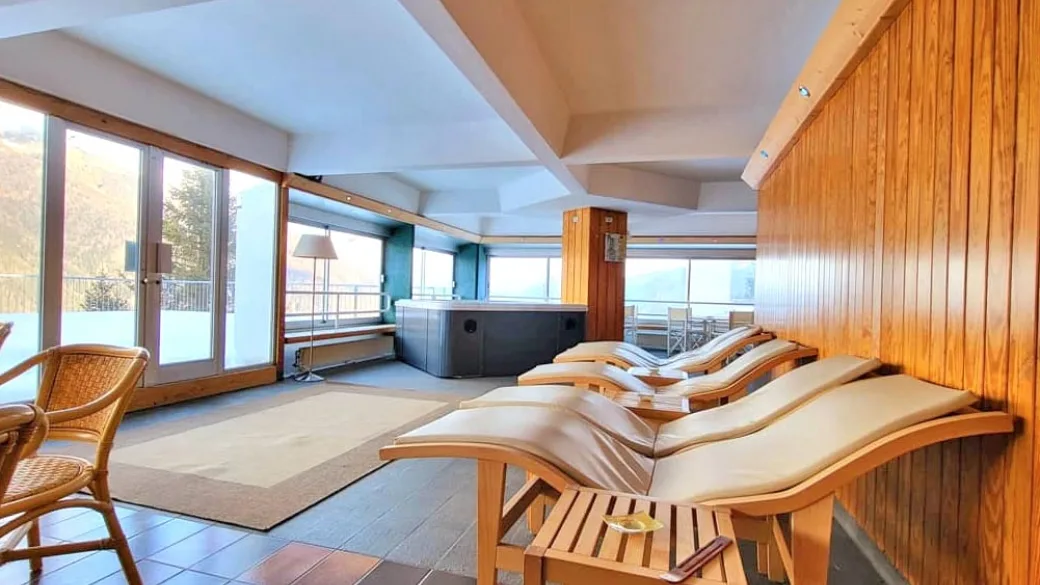 Area relax della spa con lettini in legno, idromassaggio e grandi vetrate panoramiche