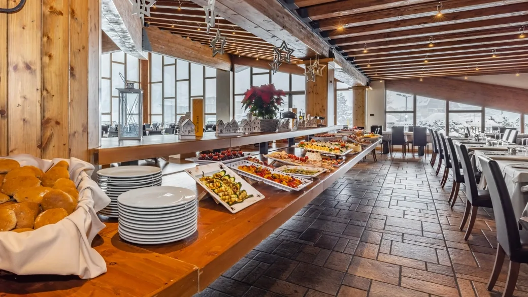 Buffet del ristorante con piatti di antipasti, pane e stoviglie, decorato per le festività con vista sulla neve