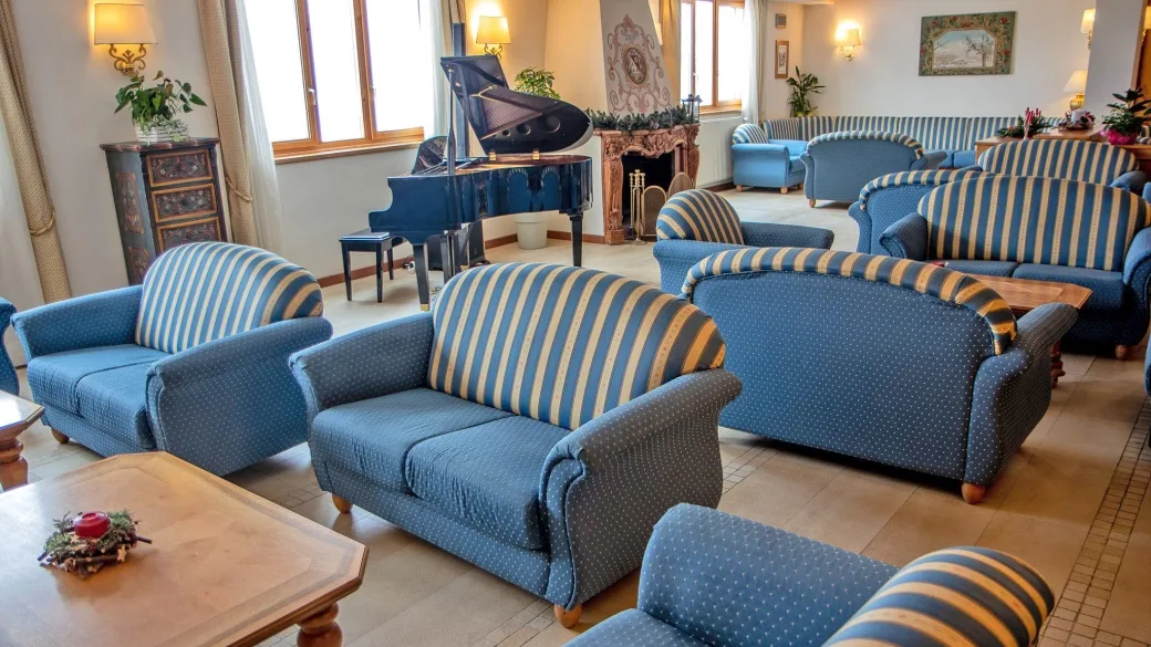 Salone soggiorno con divani a righe blu, pianoforte a coda e camino in marmo