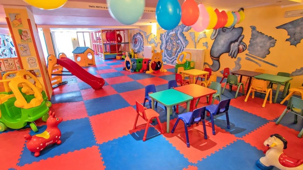 Sala giochi per bambini colorata con scivolo, giocattoli, tavolini e palloncini