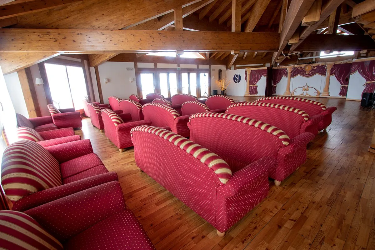 Ampia sala comune con poltrone rosse e travi in legno a vista