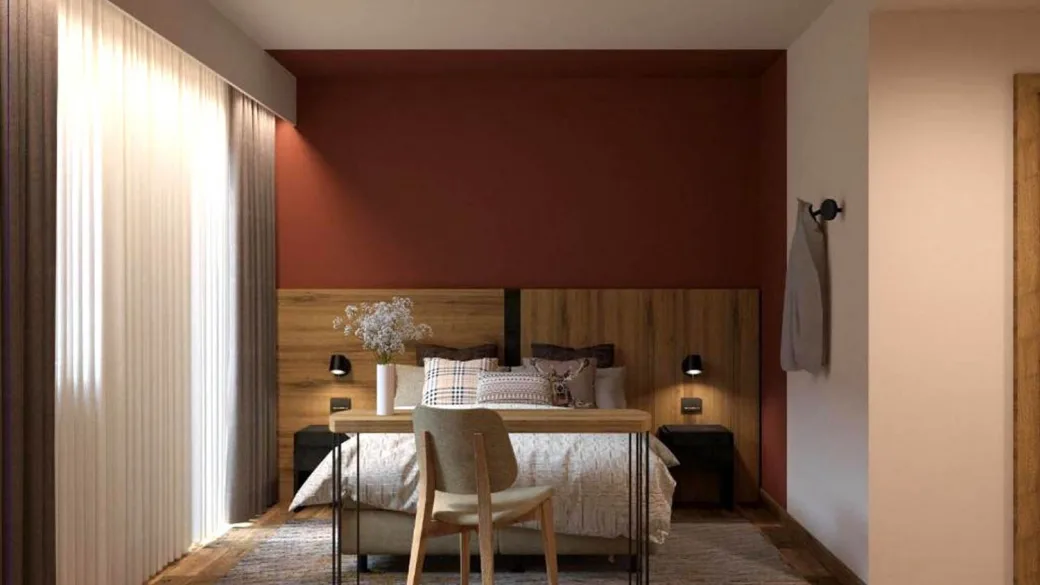 Camera da letto con parete rossa, testiera in legno e luce naturale dalla finestra