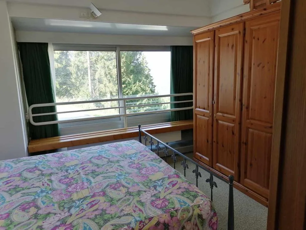 Camera da letto con letto matrimoniale, armadio in legno e finestra panoramica