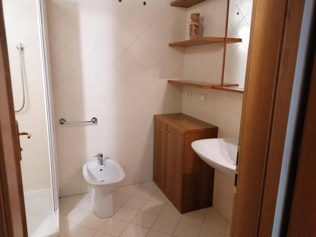 Bagno con doccia, bidet, lavabo e mobile in legno