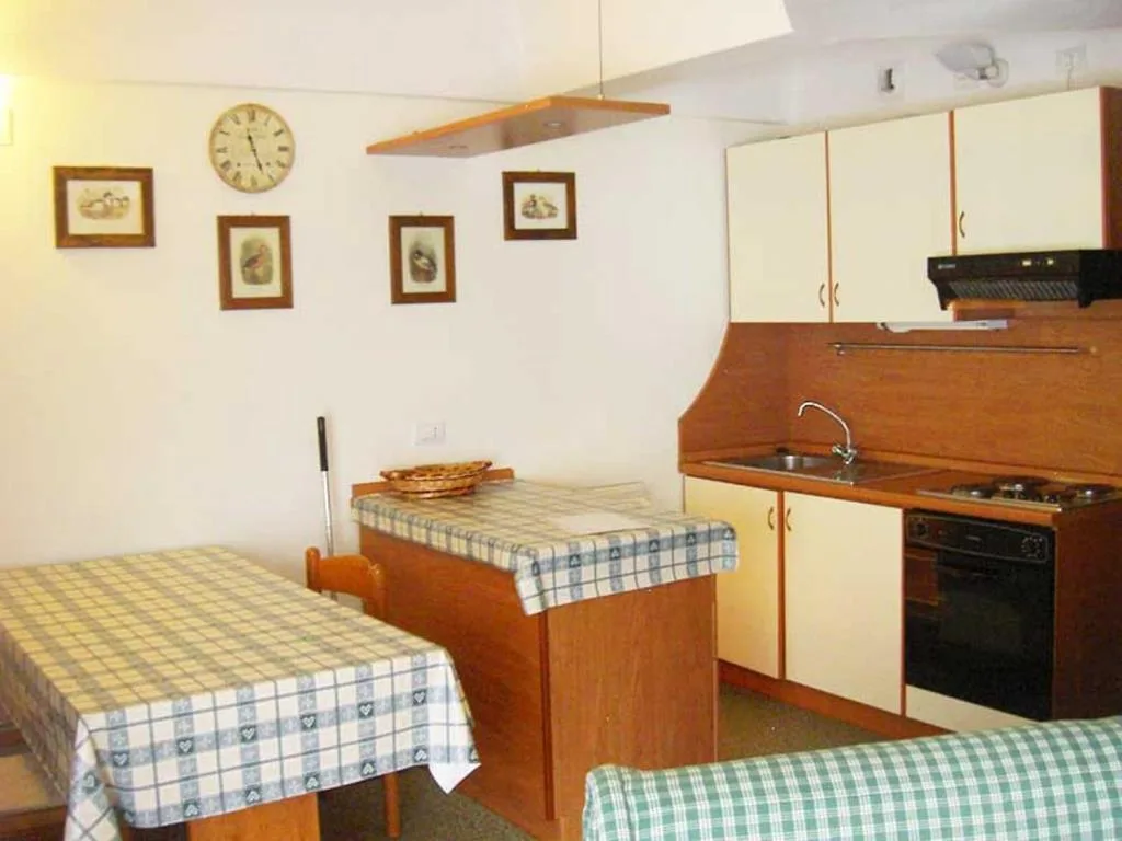 Cucina in legno con forno, tavolo da pranzo e quadri alle pareti