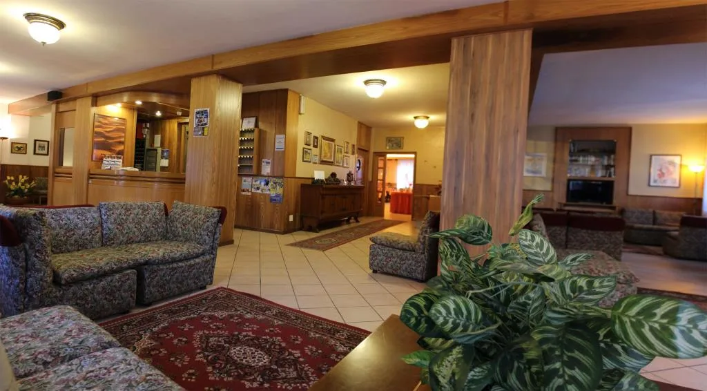 Hall dell'hotel con divani a fiori, boiserie in legno e piante ornamentali